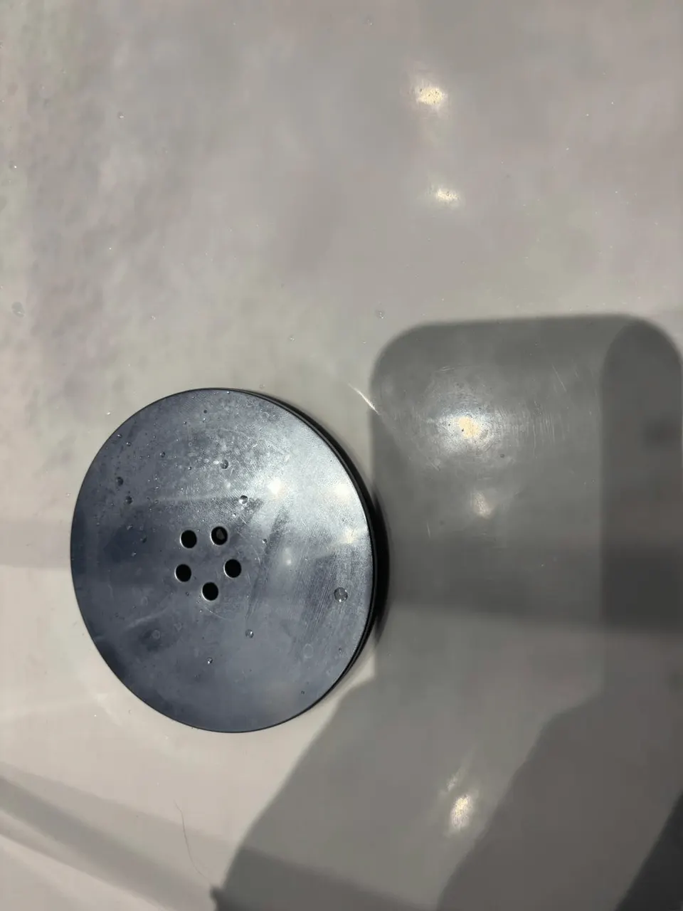 Shower drain cover marked with limescale and soap scum