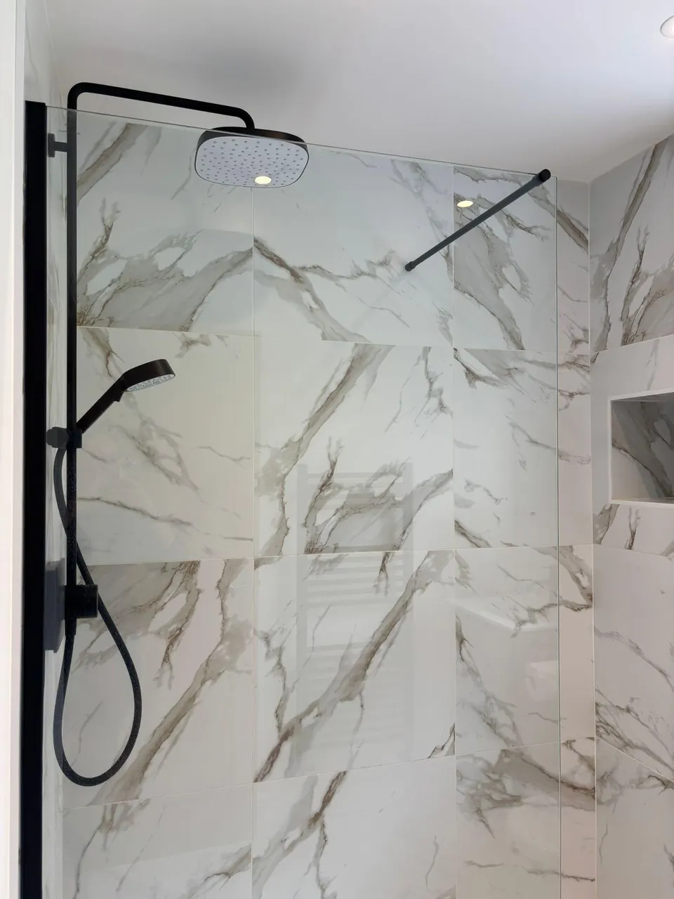 Marble walk-in shower with black fittings after a bathroom deep clean